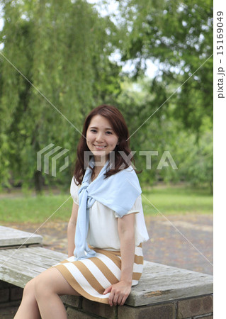 公園のベンチに腰かける女性の写真素材