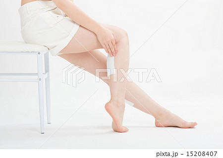 椅子に座りふくらはぎに湿布薬を貼った女性の写真素材