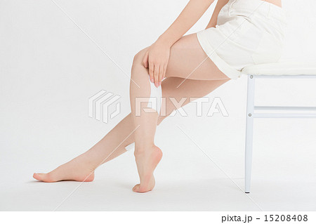 椅子に座りふくらはぎに湿布薬を貼った女性の写真素材