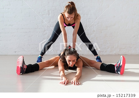 Personal trainer helping girl in leg stretching workout at gym fitness. Two women working muscles 15217339