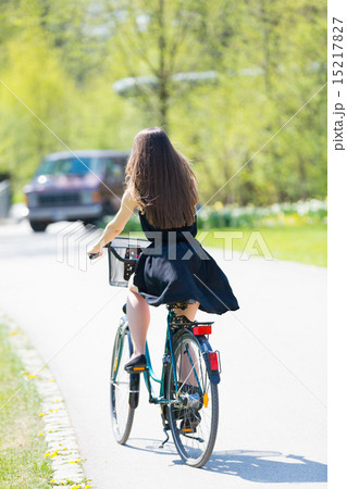 Young woman in short black dress with long hair rides a bicycle Young woman in short black dress with long hair rides a bicycle 15217827