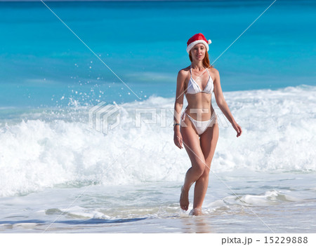 woman in a hat of Santa Claus goes on a beach woman in a hat of Santa Claus goes on a beach 15229888