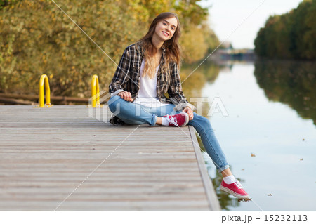 Young beautiful girl sitting on a pier 15232113