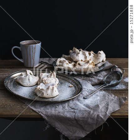 White meringue and mug of hot chocolate on a rustic wooden table. Black backdro White meringue and mug of hot chocolate on a rustic wooden table. Black backdro 15271838