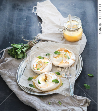 Merengues with lemon curd, fresh mint on silver tray, beige kitchen towel and grunge dark backdrop Merengues with lemon curd, fresh mint on silver tray, beige kitchen towel and grunge dark backdrop 15271841