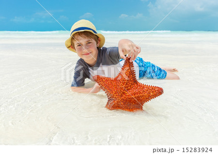 Boy and starfish on a tropical beach 15283924