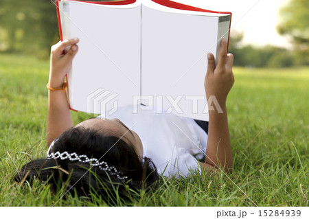 Asian little girl relax and reading a book in the park Asian little girl relax and reading a book in the park 15284939
