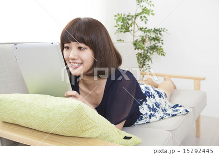 ソファでタブレットを使う若い女性イメージ 15292445