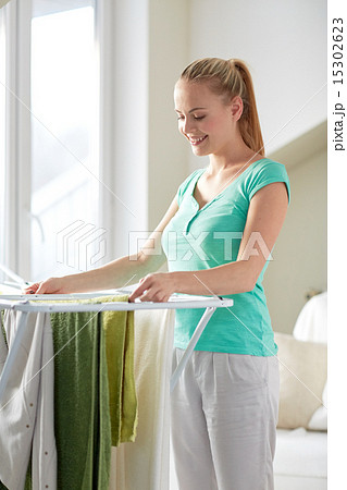 happy woman hanging clothes on dryer at home happy woman hanging clothes on dryer at home 15302623