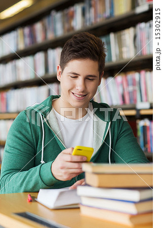 male student with smartphone texting in library 15302915