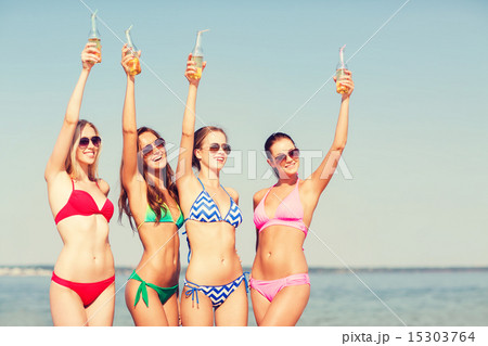 group of smiling young women drinking on beach 15303764