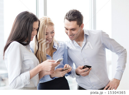 smiling business team with smartphones in office 15304365