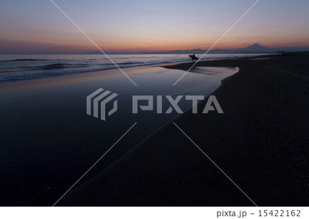 夕暮れの海岸を歩くサーファー 15422162