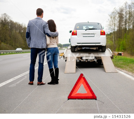 Couple near tow-truck picking up broken car 15431526
