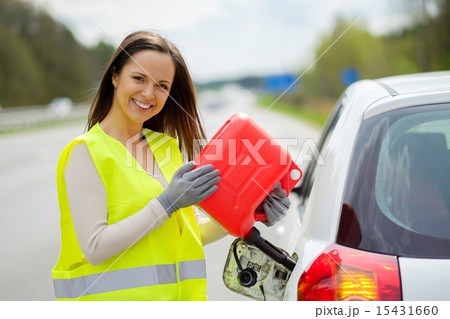Woman refuelling her car on a highway roadside 15431660