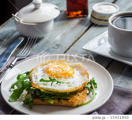 crispy toast with a fried egg and green arugula 15431950