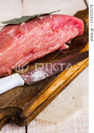 pork on a bay leaf, knife and salt on a wooden 15432078