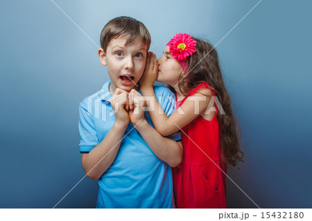 Teenage girl whispering in the ear of a secret teen boys on a g Teenage girl whispering in the ear of a secret teen boys on a g 15432180