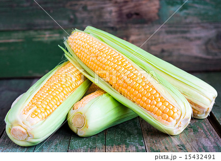 raw corn on the cob on a green wooden background 15432491