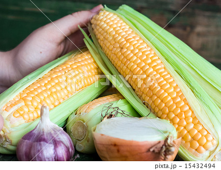raw corn on the cob on a green wooden background 15432494
