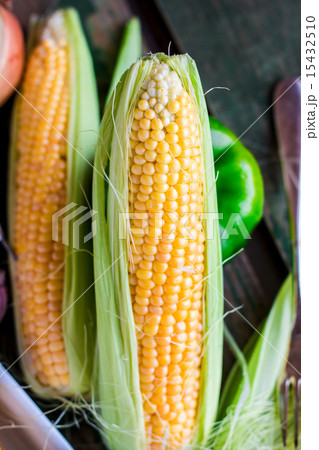 raw corn on the cob on a green wooden background 15432510