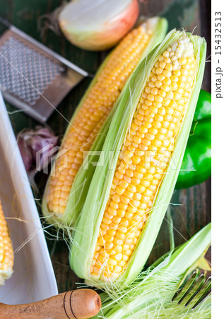 raw yellow corn on the cob on a green 15432513