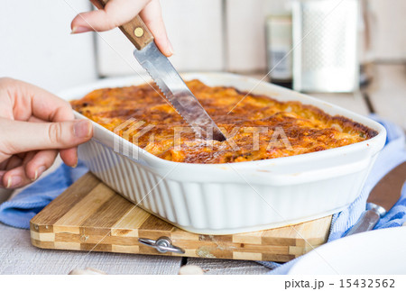 cut meat lasagna in the form of baking, hands 15432562