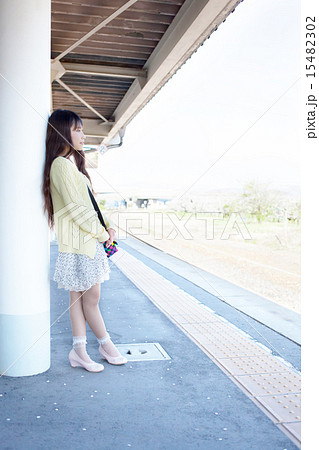 田舎の無人駅で電車を待つ若い女性の写真素材