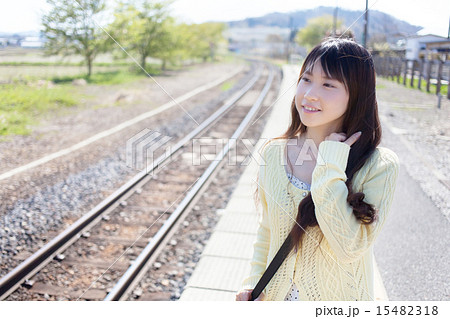 田舎の無人駅で電車を待つ若い女性の写真素材