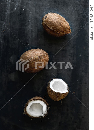 Whole and broken coconuts over dark background 15484049