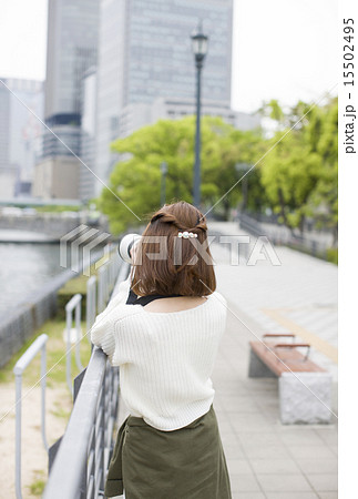 大阪中之島公会堂付近の川沿いでカメラを構え撮影の練習をする若い女性 15502495