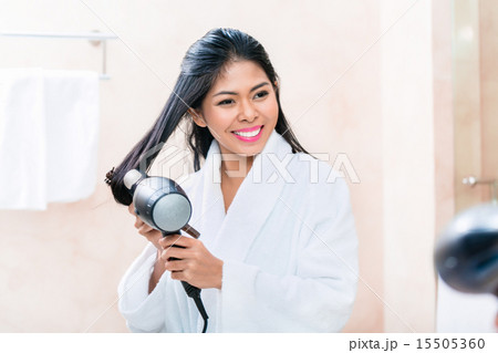 Asian woman in bathroom drying hair Asian woman in bathroom drying hair 15505360