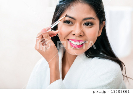 Asian woman in bathroom plucking eyebrows 15505361