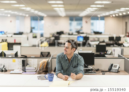 A young man seated at a desk in an office. 15519340