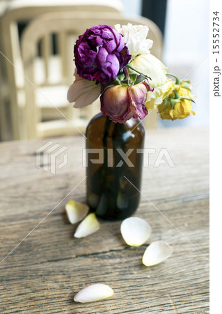 Wither roses in bottle on wooden table 15552734