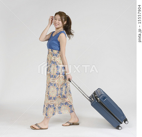 キャリーバッグを引く若い女性の写真素材