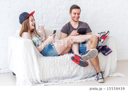 Young friends funny guys active people have fun together sitting on sofa send message chatting using 15558439