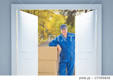 Composite image of happy delivery man leaning on pile of cardboa 15569808