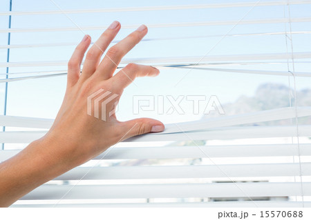 Curious person watching through venetian blind 15570688