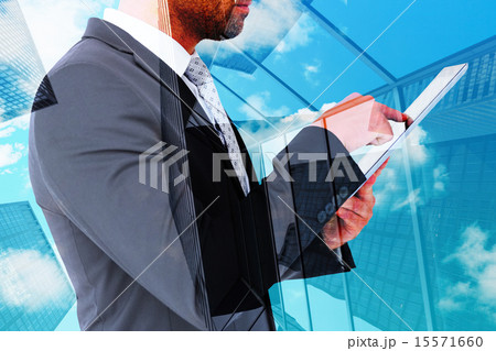 Composite image of businessman using his tablet pc Composite image of businessman using his tablet pc 15571660