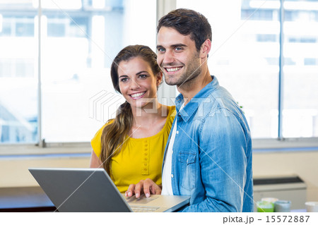 Casual business partners holding laptop Casual business partners holding laptop 15572887