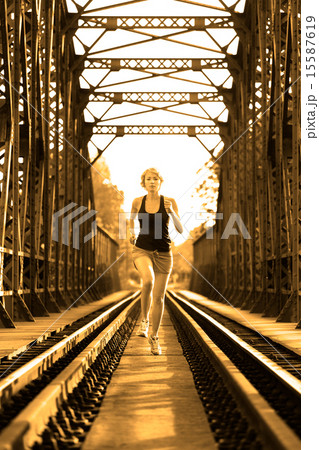 Active female athlete running on railaway tracks. 15587619