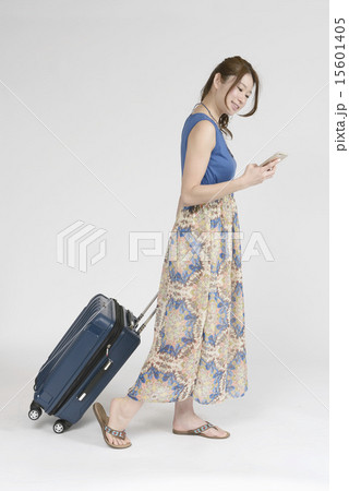 キャリーバッグを引きながらスマホを見る女性 キャリーバッグを引きながらスマホを見る女性 15601405