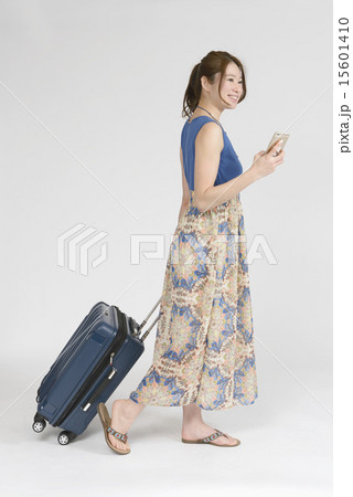 キャリーバッグを引きながらスマホを見る女性 15601410
