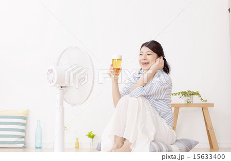 扇風機にあたりながらビールを飲む女性 15633400