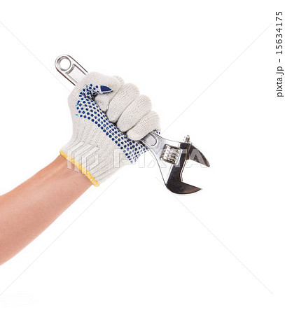 Hand in gloves holding adjustable wrench. 15634175