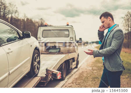 Man calling while tow truck picking up his broken car Man calling while tow truck picking up his broken car 15645300