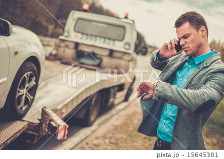 Man calling while tow truck picking up his broken car Man calling while tow truck picking up his broken car 15645301