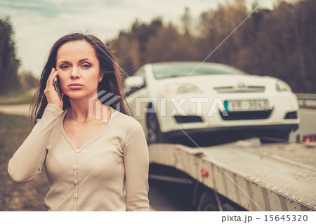 Woman calling while tow truck picking up her car Woman calling while tow truck picking up her car 15645320