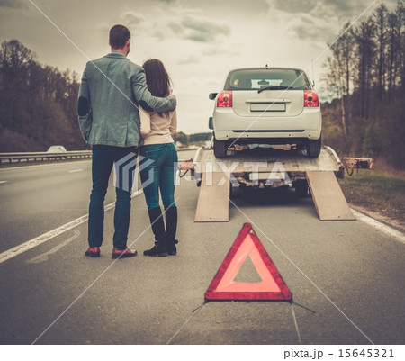 Couple near tow-truck picking up broken car Couple near tow-truck picking up broken car 15645321